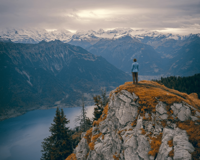 A person stands on top of a cliff looking out on a vast panoramic scene. Photo by Felipe Giacometti on Unsplash.