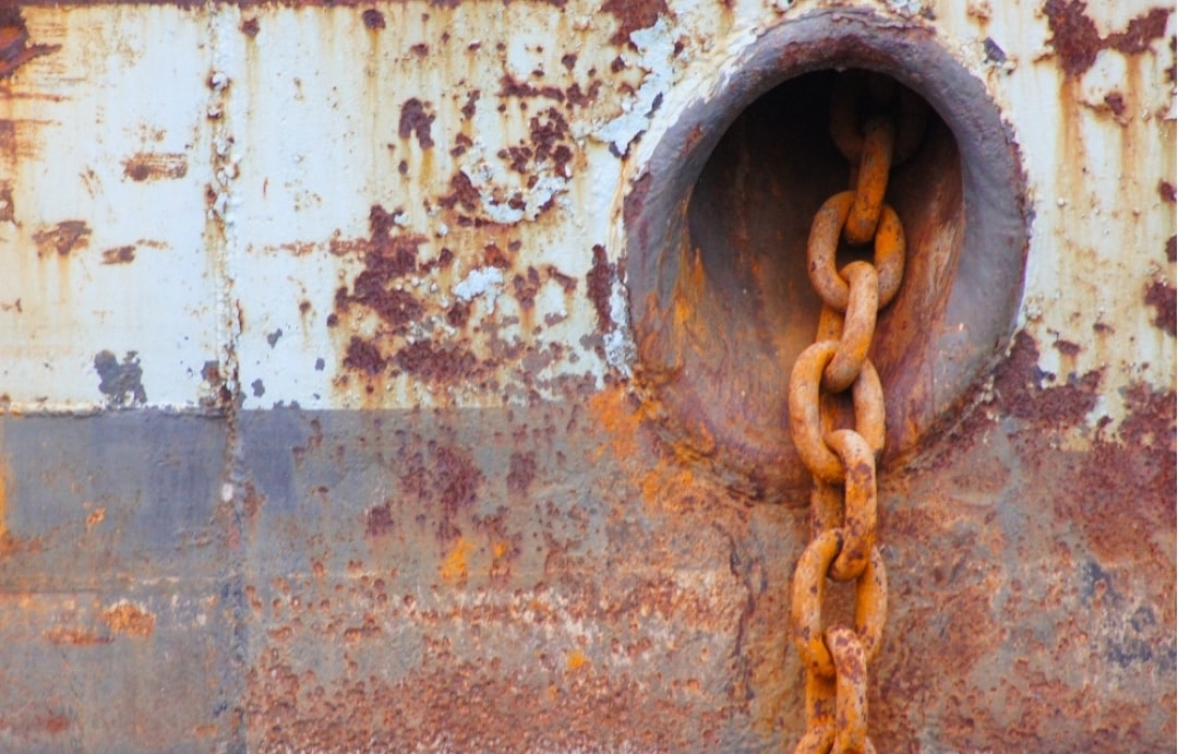 A ship's chain against a rusty ship.