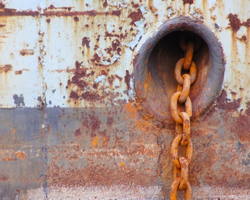 A ship's chain against a rusty ship.