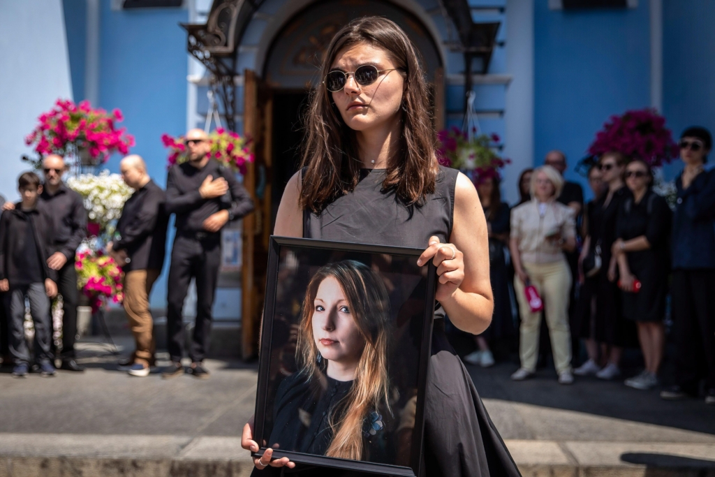 A woman holds a photo of Victoria Amelina outside her funeral at the St. Michael's Golden-Domed Monastery in Kyiv. Photo by SOPA Images Limited c. Alamy.