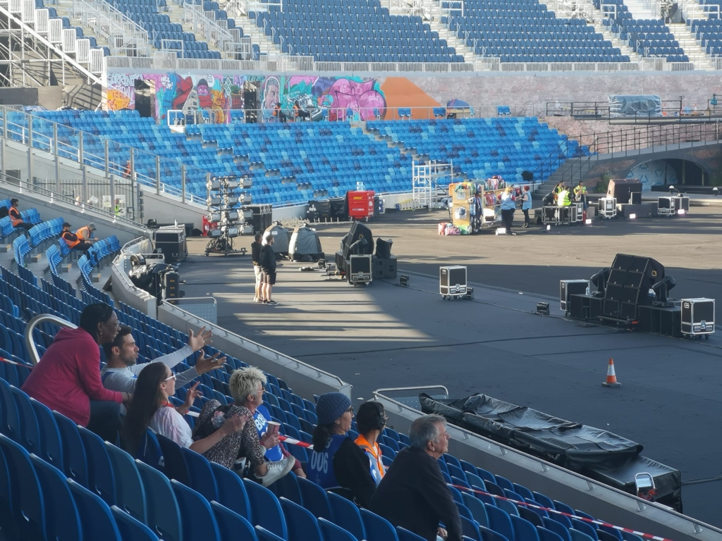 Maeve Clarke (back row), the Bards of Birmingham volunteers aka 'the BoBs,' and members of the Creative and Technical Teams – review progress at Alexander Stadium.